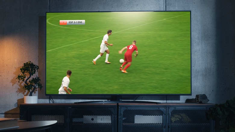 A soccer match on a large television on a TV stand