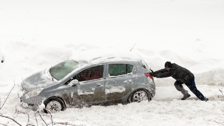 Person pushing car in snow
