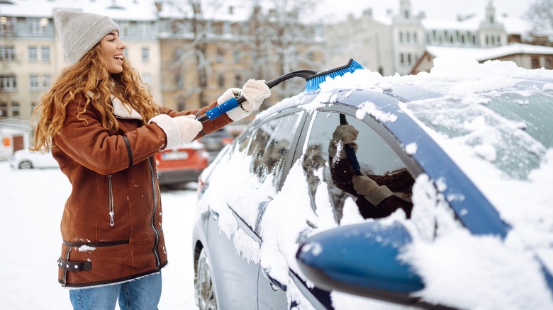 woman cleaning snow from car