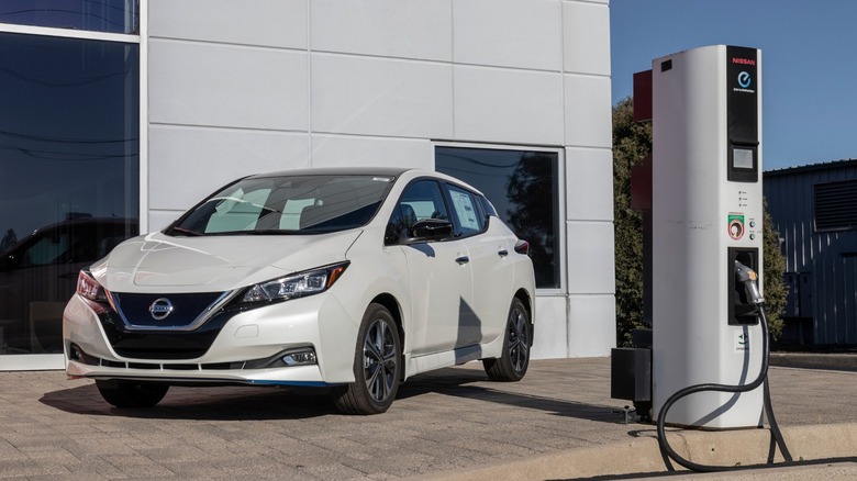 White Nissan Leaf beside an electric charging station