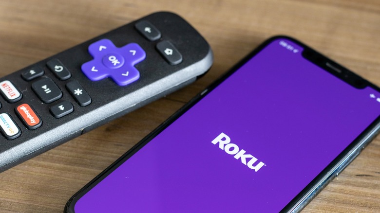 Roku remote next to the Roku app on a mobile device
