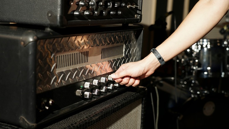 guitarist changing knobs on an amplifier head